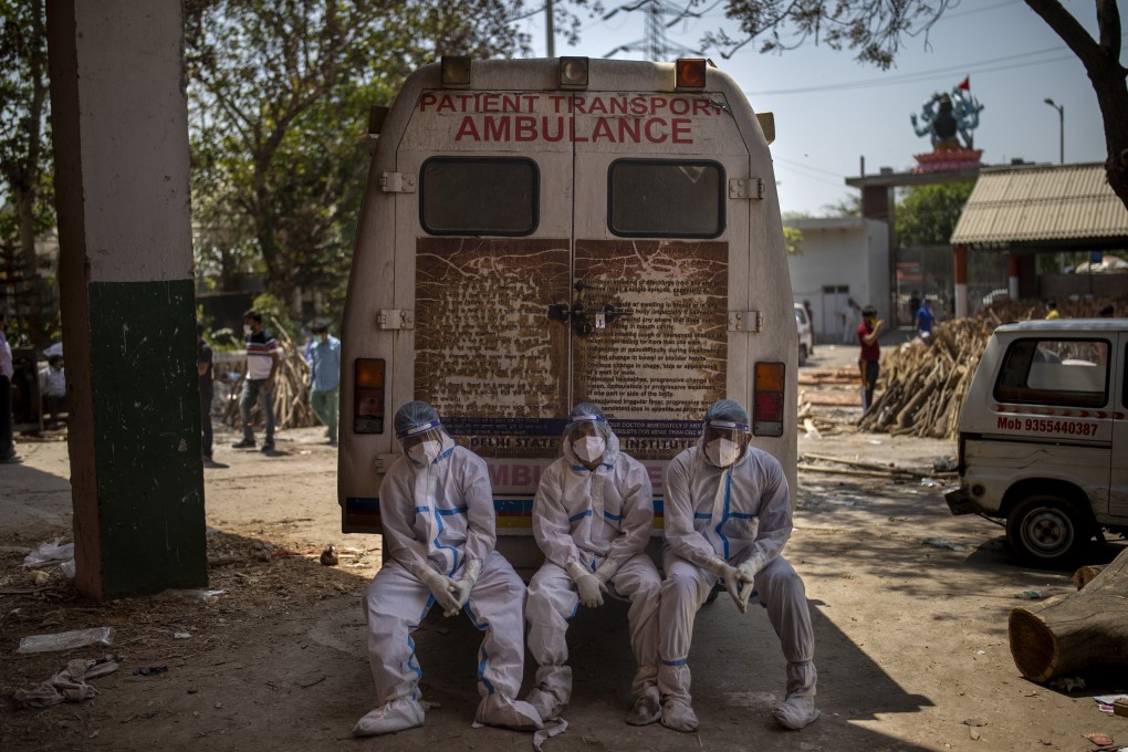 Exhausted workers, who bring dead bodies for cremation, sit on the rear step of an ambulance inside a crematorium in New Delhi, India. Photo: AP