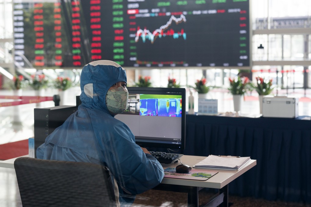 A worker wearing a protective suit reacts in front of an infrared temperature machine in the lobby of the Shanghai Stock Exchange building in February 2020. Photo: AP