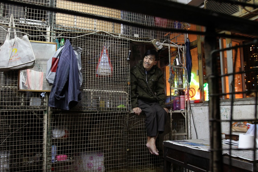 A man sits in a cage dwelling in Mong Kok on December 3, 2013. Photo: SCMP