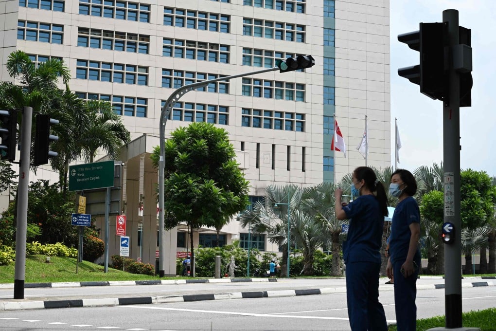 Medical staff wait at a traffic light outside Singapore’s Tan Tock Seng Hospital, as authorities try to contain the spread of a coronavirus cluster detected at the facility. Photo: AFP