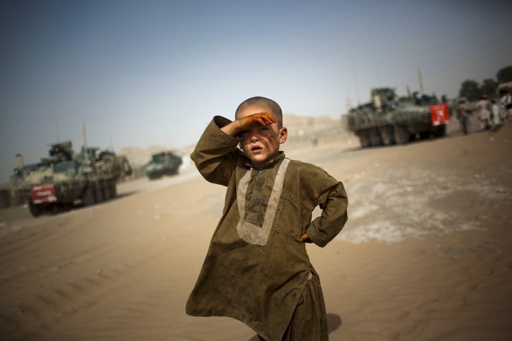 A child looks on as American military vehicles pass his village on the outskirts of Spin Boldak, southeast of Kandahar, Afghanistan. Photo: AP
