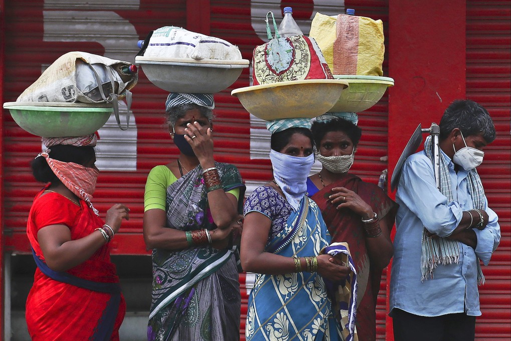 Labourers wearing protective face masks wait for transport to work in Hyderabad, India. Photo: AP