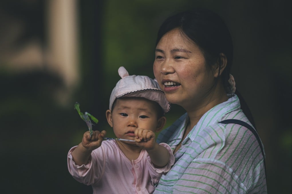 A woman walks with a baby on a street in Shanghai, after China announced it would allow each couple to have three children, to boost population growth. Photo: EPA-EFE