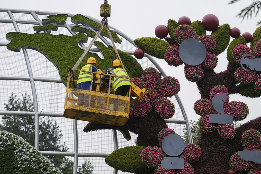 Workers in Beijing set up flower decorations with a map showing the US, on June 13. Leaders of the world’s largest economies have unveiled an infrastructure plan for the developing world to compete with China’s global initiatives. Photo: AP