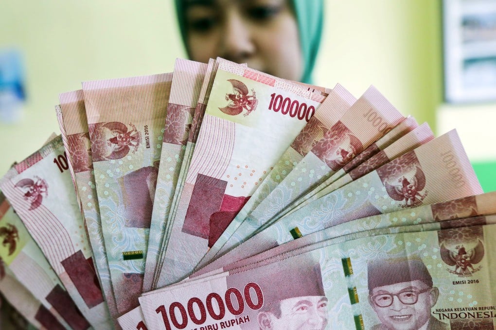 A worker holds Rupiah banknotes at a money exchange point in Medan, North Sumatra, Indonesia. Photo: EPA