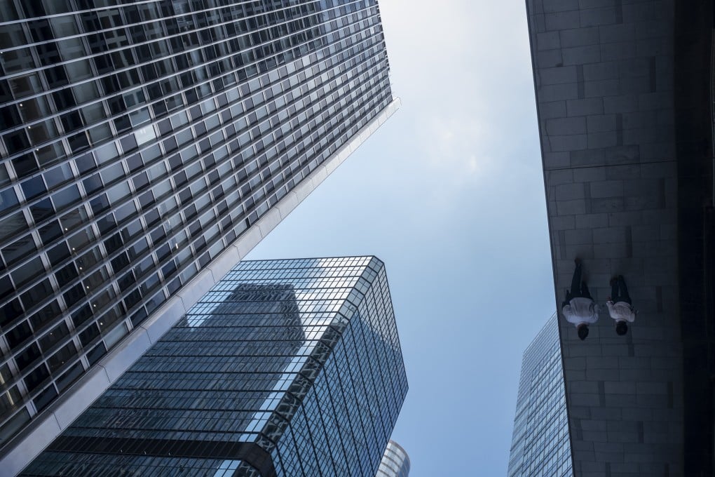 People are seen reflected in an awning next to office buildings in Hong Kong’s Central district on June 7. Photo: Bloomberg