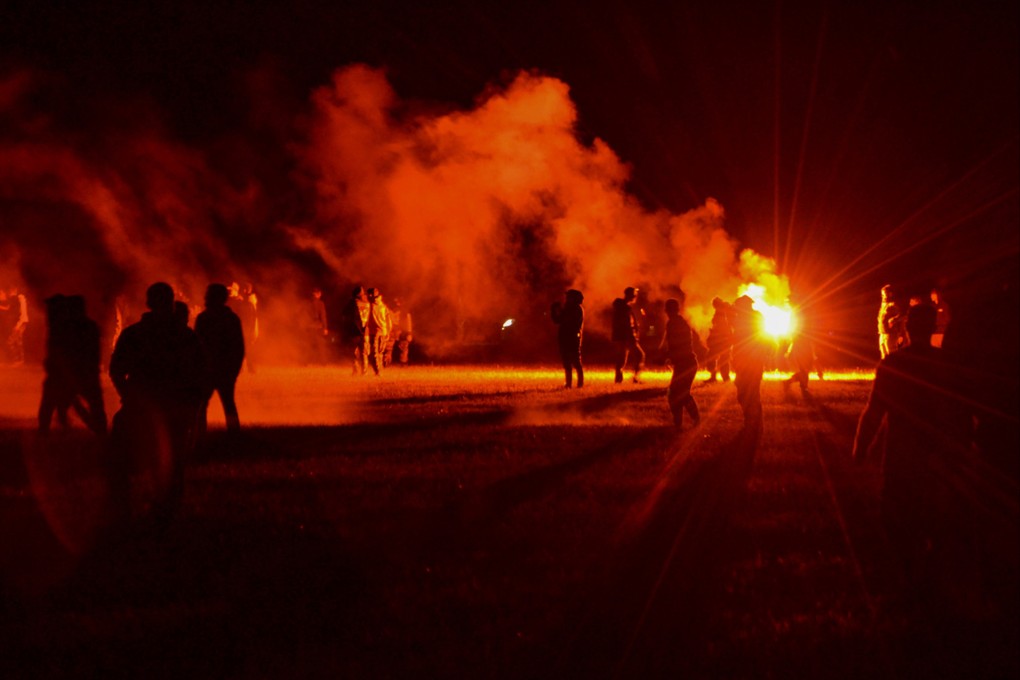 Partygoers stand in a field as police try to break up an illegal rave near Redon, Brittany, France on Friday. Photo: AP