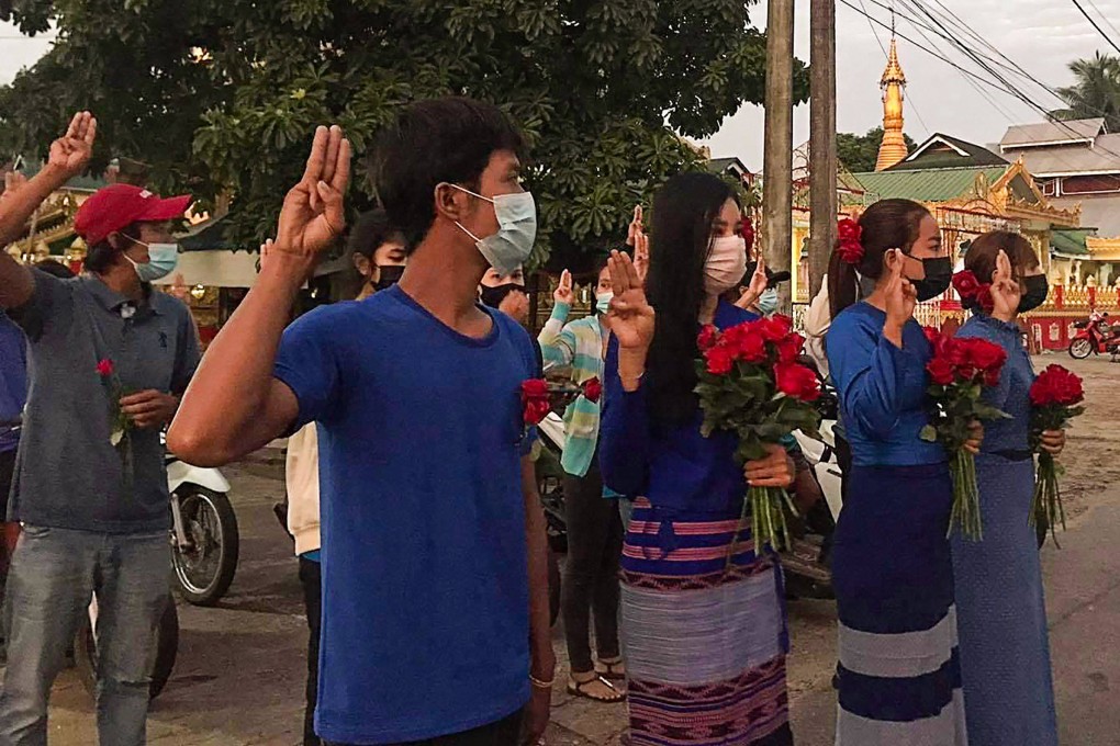Myanmar protesters holding roses, to show solidarity with those who have been arrested, make the three-finger salute during a demonstration against the military coup. Photo: AFP