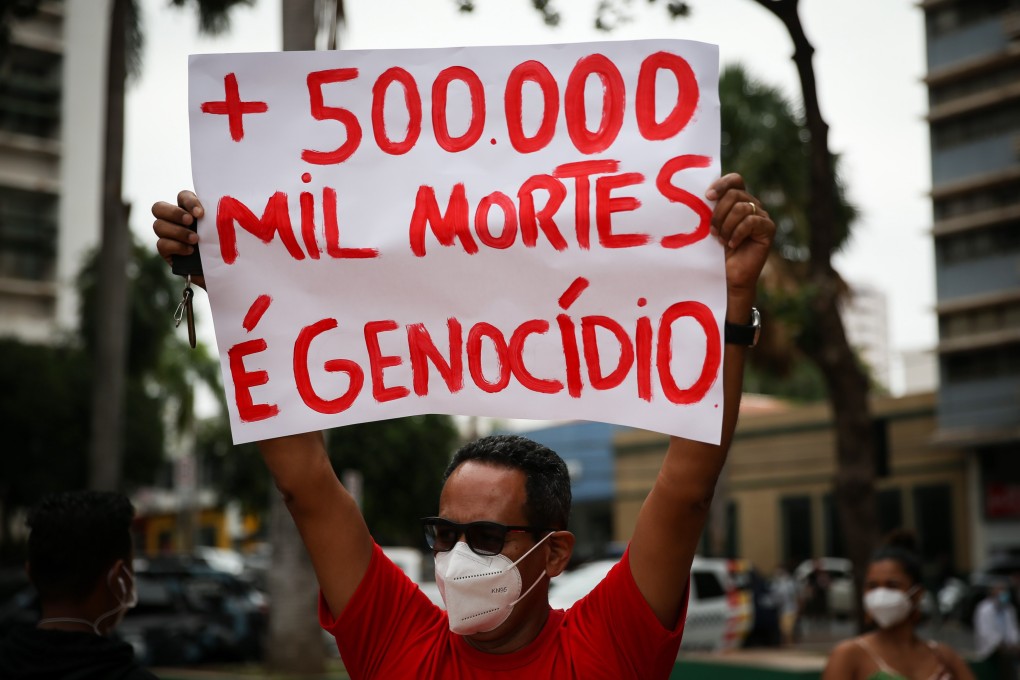 A protester holds a sign reading ‘500,000 deaths and genocide’  in Cuiaba, Brazil on Saturday. Photo: EPA-EFE