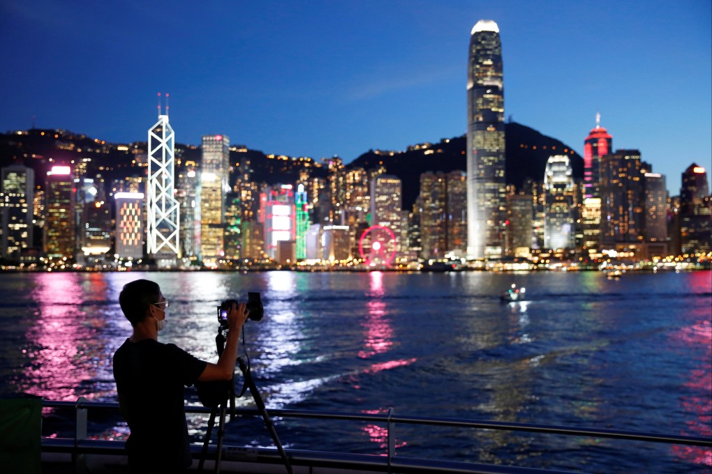 A man wearing a mask takes a photo of sunset on Hong Kong’s waterfront. Photo: Reuters