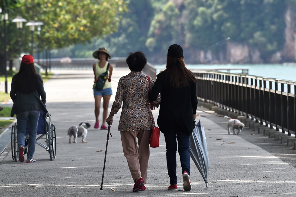 A carer walks with an elderly woman in a park in Singapore in September 2016. Photo: AFP