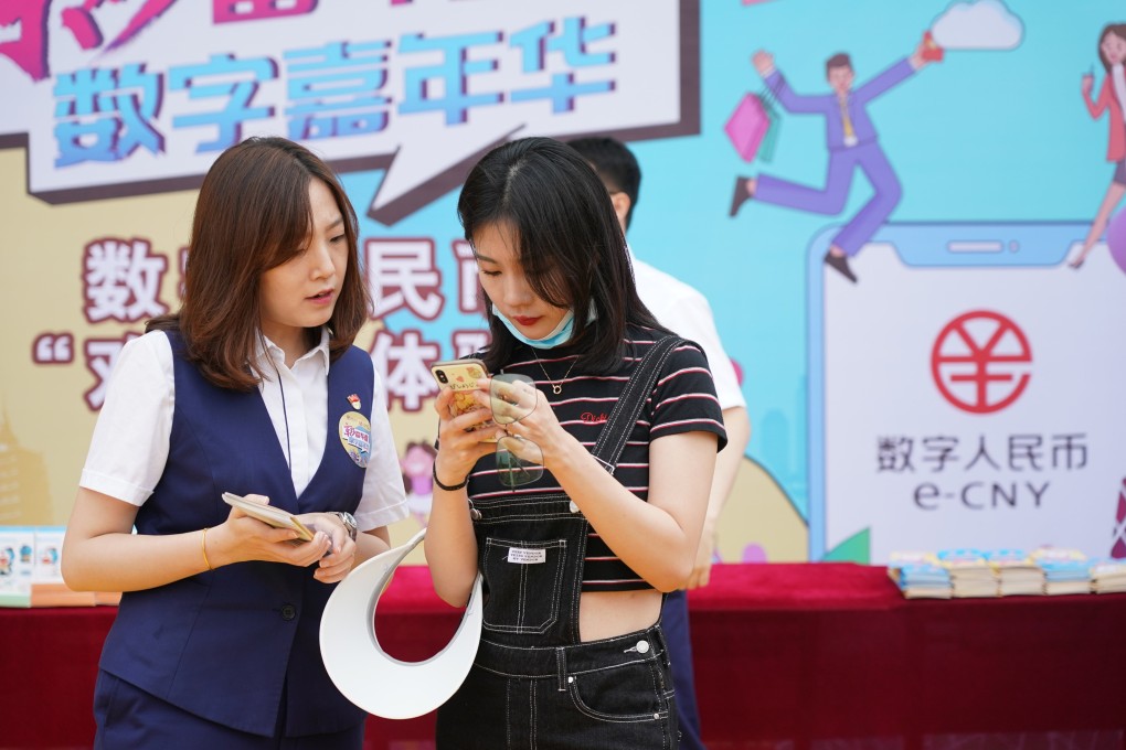 A Bank of Communications employee looks on as a customer tries the digital yuan online wallet at the Happy Valley Beijing theme park, in Beijing, on June 16. Trials have been rolled out across the country for the digital yuan. Photo: Xinhua
