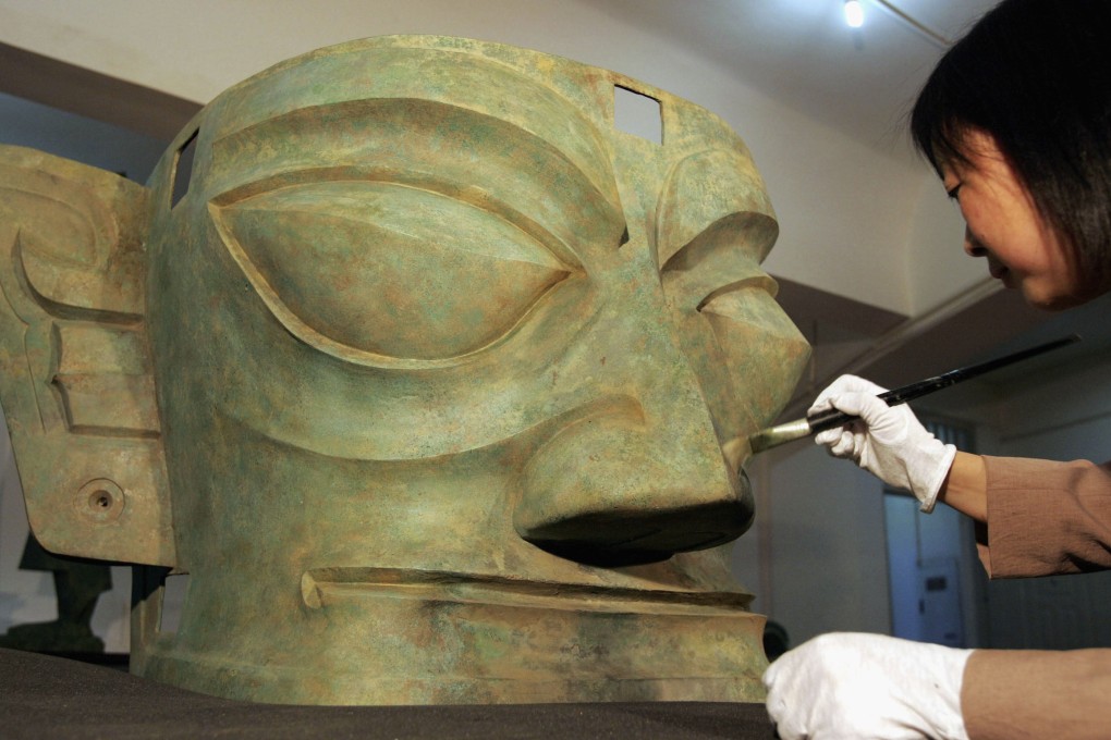 A museum worker cleans a bronze relic, which was excavated in 1986, at the Sanxingdui Museum on April 13, 2005 in Guanghan, Sichuan province, southwest China. Some believe this and other artefacts unearthed in Sanxingdui point to alien life. Photo: Getty Images