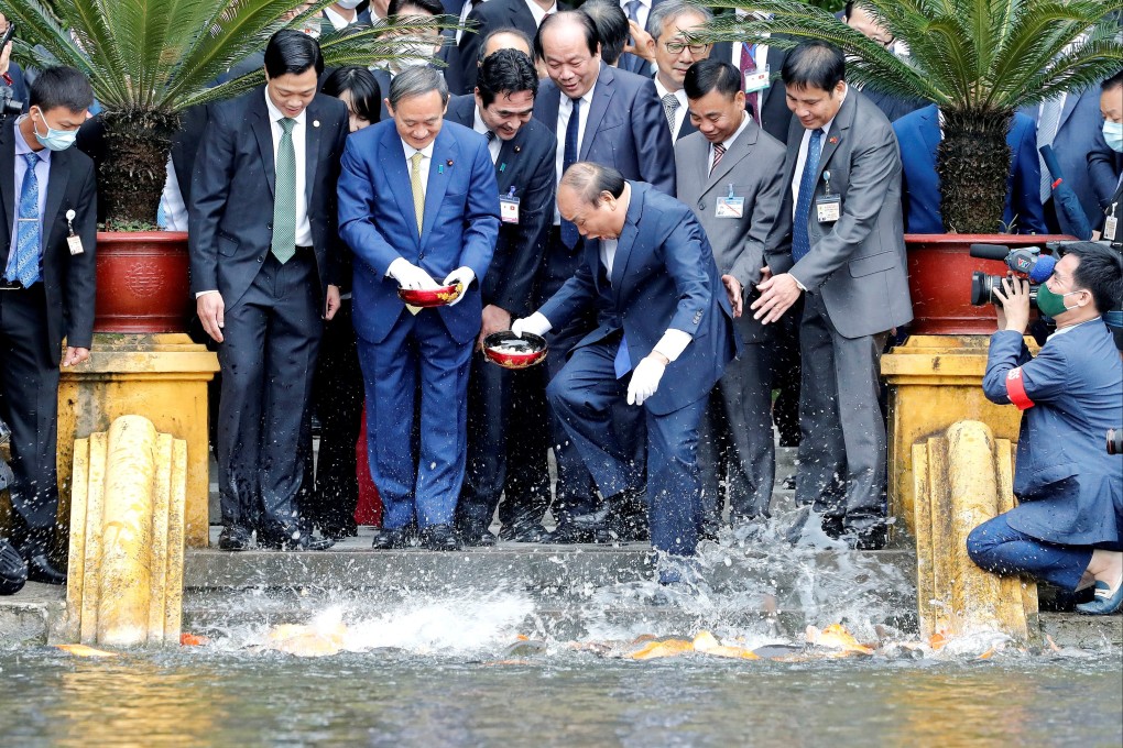 Japanese Prime Minister Yoshihide Suga and his then Vietnamese counterpart Nguyen Xuan Phuc feeding the fish in a pond at the Presidential Palace in Hanoi on October 19, 2020. Photo: Reuters