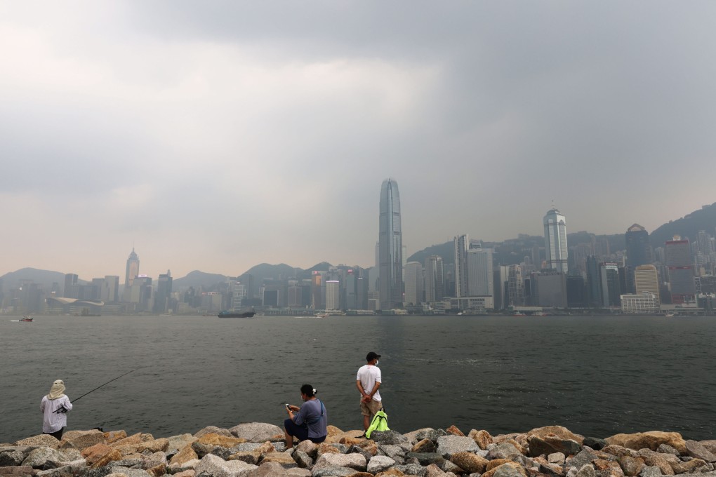 People look towards Hong Kong Island from the waterfront at the West Kowloon Cultural District as air pollution hangs over the city. Photo: May Tse