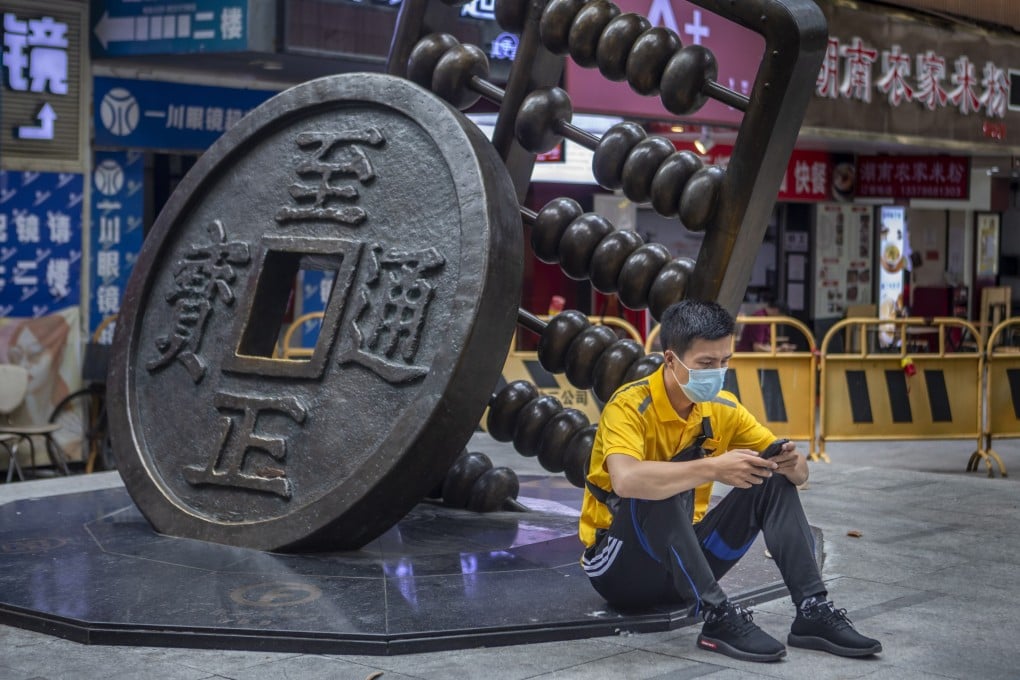 A man next to a sculpture representing the renminbi and an abacus in Guangzhou, China. Photo: EPA