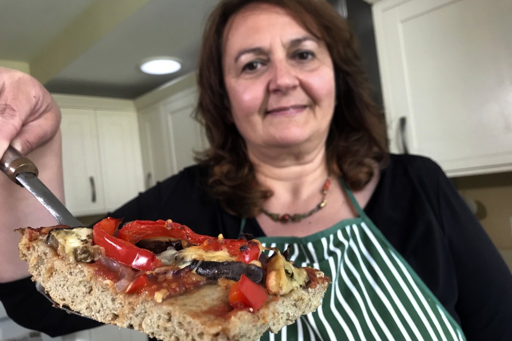 Tiziana di Costanzo, co-founder of Horizon Insects, holds up a slice of pizza made with cricket powder, in her London kitchen. Photo: AP
