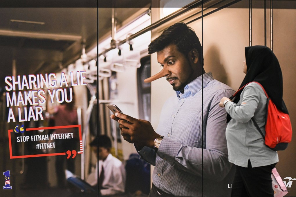A commuter ponders an advertisement for Malaysia’s campaign against fake news in March 2018. Photo: AFP
