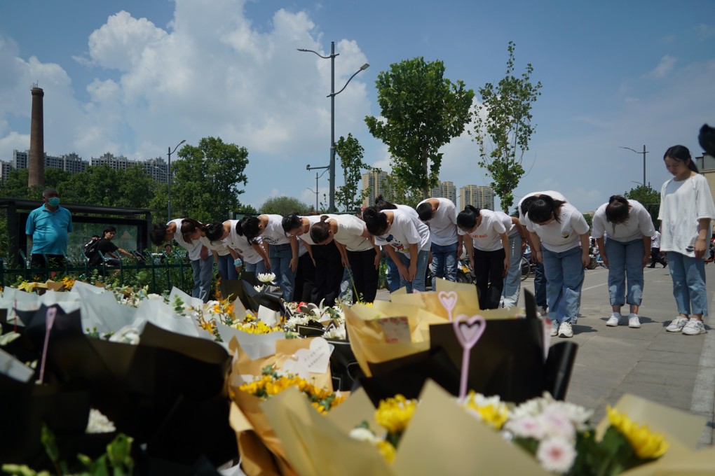 People bow to pay their respects outside the entrance to a subway station in Zhengzhou in central China’s Henan province on July 27. At least 14 people at the station died after record-breaking rainfall flooded underground railway tunnels, leaving passengers trapped in rising waters. Photo: AP