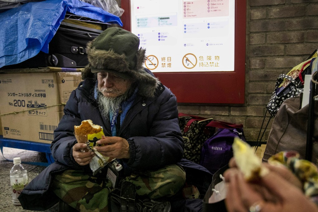 A 76-year-old homeless man eats a late dinner with a friend before bedding down for the night at Shinjuku Station in Tokyo in January 2020. Photo: AP
