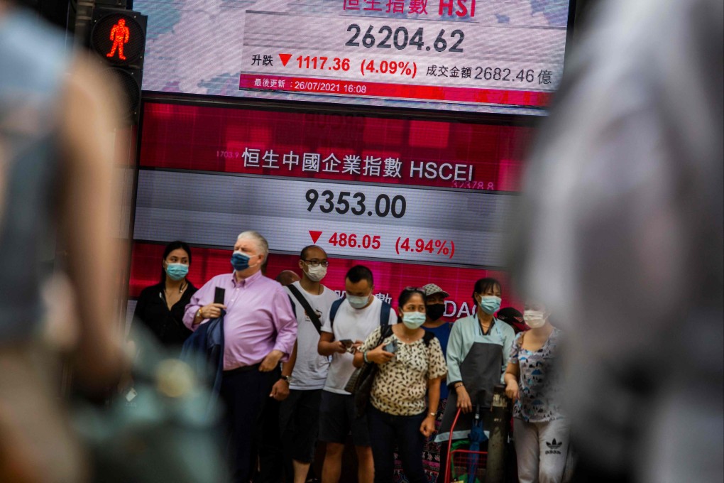 People stand in front of an electronic display showing the Hang Seng Index in Central on July 26 after stocks plunged as tuition firms were hammered by China’s decision to reform the private education sector by preventing them from making profits. Photo: AFP