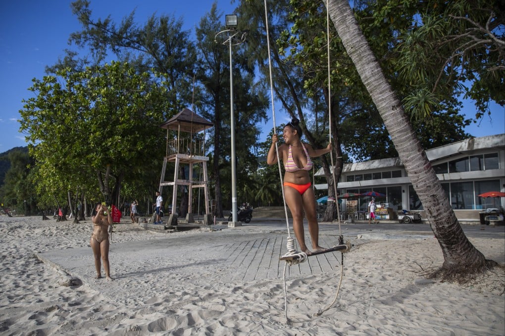 Locals pose for photos on Patong Beach on July 19 in Phuket, Thailand. The island is part of a quarantine-free programme for vaccinated tourists called “Phuket Sandbox”. Photo: Getty Images