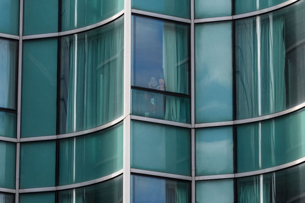 A woman poses at the window of her Hong Kong hotel room during her three weeks of mandatory quarantine. Scientific research shows the requirement can have lasting negative effect on mental health. Photo: AFP