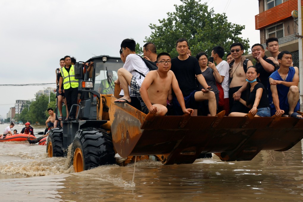 People ride a front loader as they make their way through a flooded road following heavy rainfall in Zhengzhou, Henan province, on July 22. Photo: Reuters