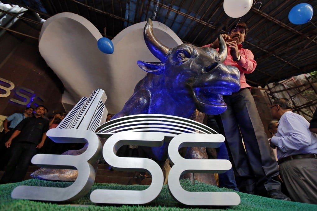 A man ties a balloon to the horns of a bull statue at the entrance to the Bombay Stock Exchange in Mumbai, India, in April 2017. Photo: Reuters