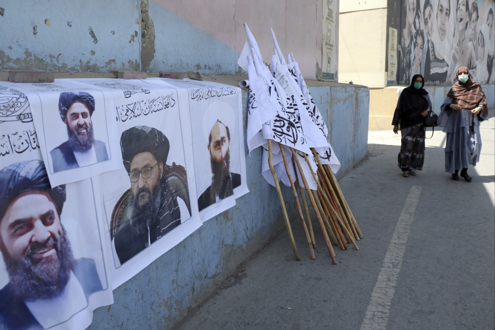 Afghan women approach posters of Taliban leaders and flags in Kabul on August 25. Photo: AP