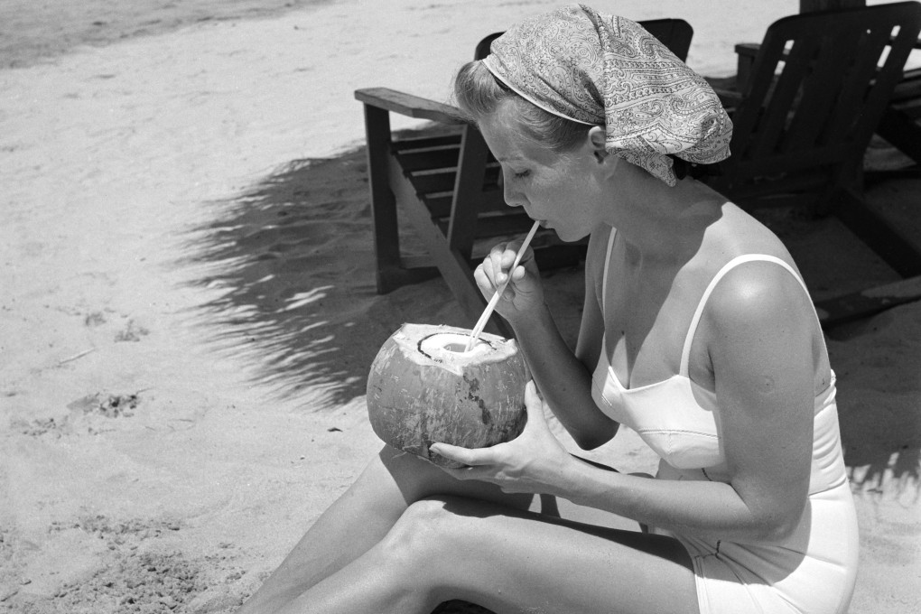 A woman sips from a coconut on a beach in Acapulco, Mexico, in a 1952 photo by Earl Leaf. How the fruit acquired its name in English is a curious tale. Photo: Michael Ochs Archives/Getty Images