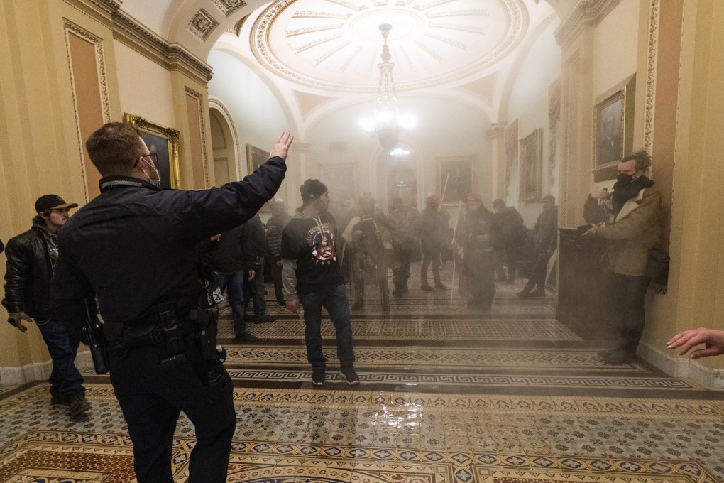 Smoke fills the walkway outside the Senate Chamber as rioters are confronted by US Capitol Police officers in Washington on January 6, 2021. Photo: AP