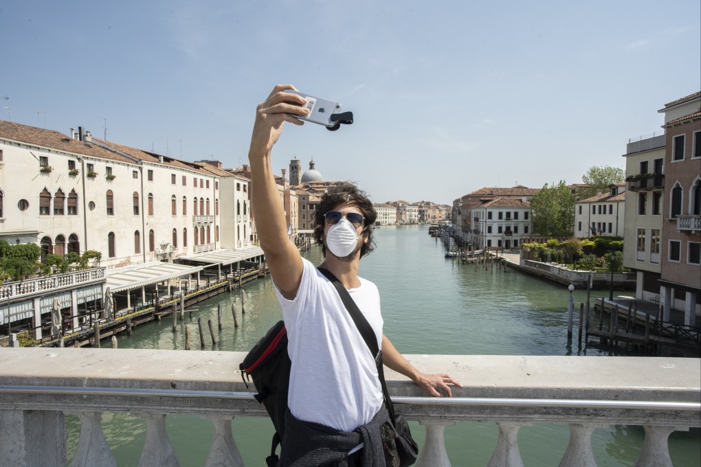 A visitor takes a selfie on a bridge over the Grand Canal in Venice. Day-trippers will soon be charged to enter Venice, and their movements will be tracked. Photo: Getty Images