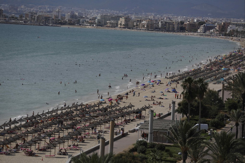 Holidaymakers relax on the beach at Arenal, in Mallorca, Spain. Photo: Getty Images