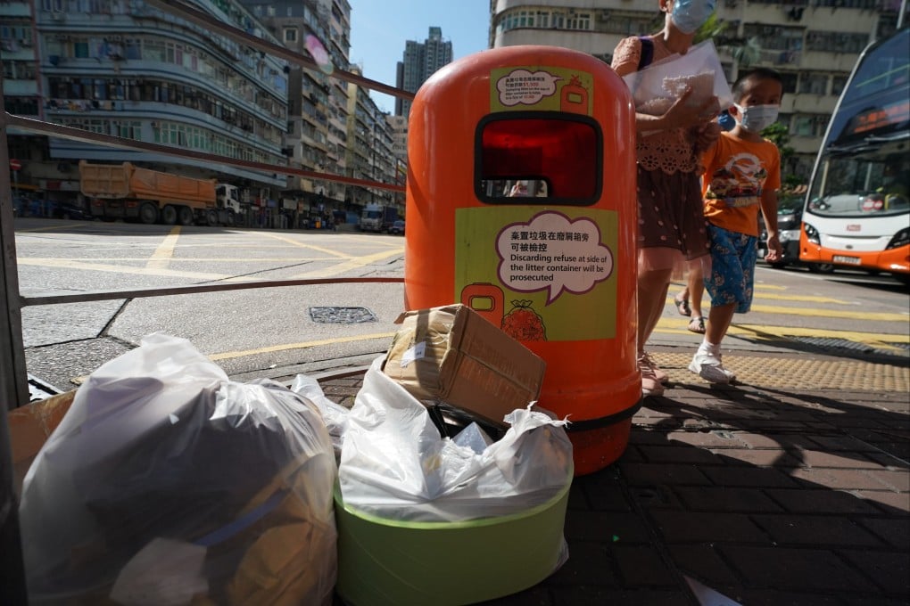 People pass by bags of waste next to a rubbish bin in Sham Shui Po. The waste charging bill has been approved by lawmakers after 16 years, but without an effective start date. Photo: Felix Wong