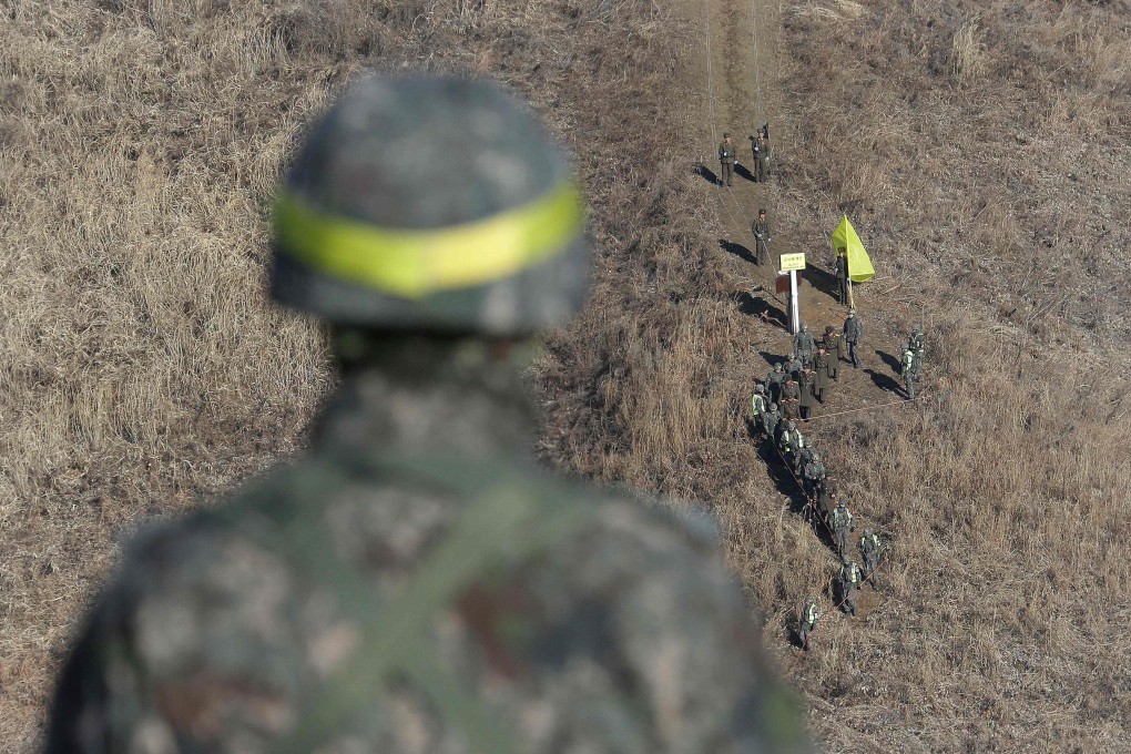 A North Korean soldier (top) is greeted by South Korean soldiers before crossing the military demarcation line inside the demilitarised zone to inspect the dismantled North Korean guard post in the central section of the inter-Korean border in Cheorwon, South Korea, on December 12, 2018. Photo: AFP