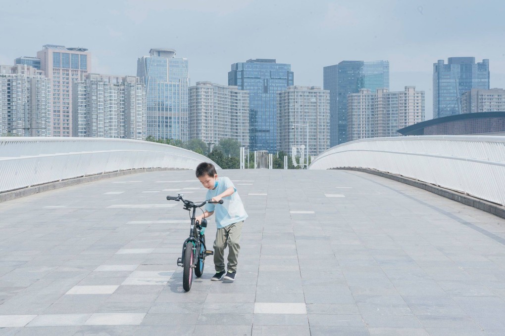 A boy pushes his bike along the bridge that connects the Hongbaihua Park and Ruyi Lake Cultural Square in Zhengzhou, China, in August. Photo: Bloomberg Businessweek / Yufan Lu