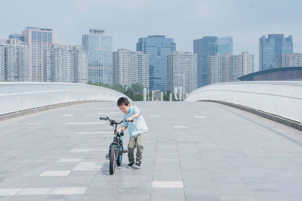 A boy pushes his bike along the bridge that connects the Hongbaihua Park and Ruyi Lake Cultural Square in Zhengzhou, China, in August. Photo: Bloomberg Businessweek / Yufan Lu
