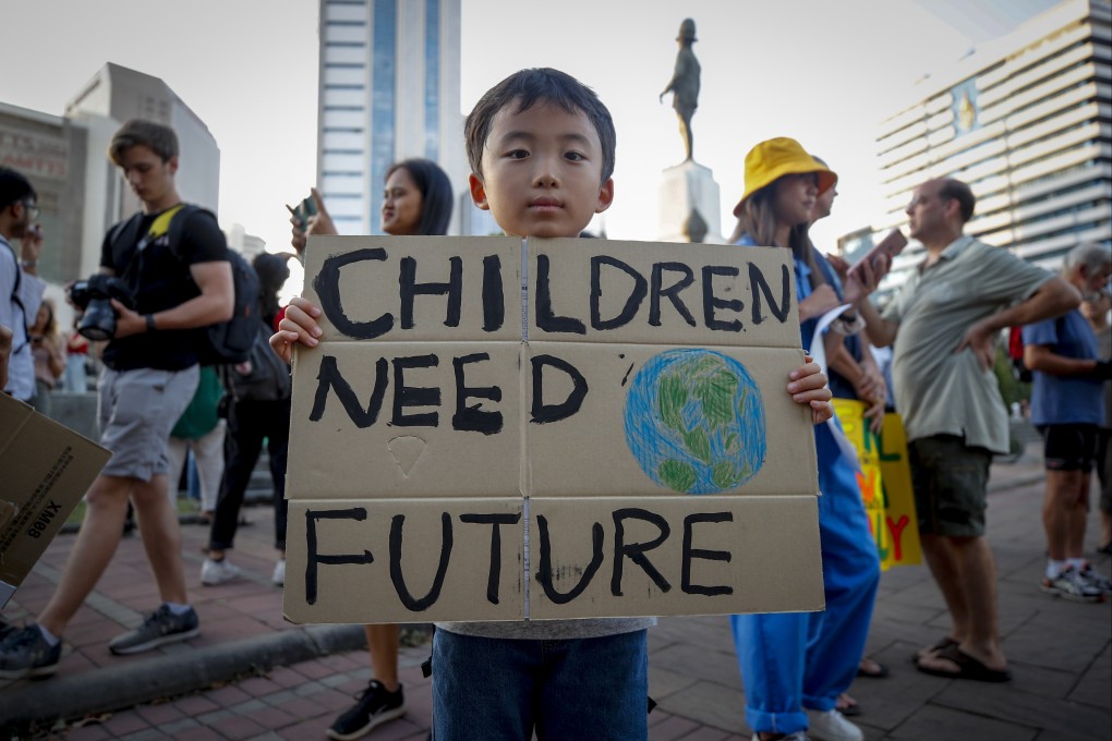 A young boy holds a sign outside a park during a climate change strike in Bangkok, Thailand, on November 29, 2019. Photo: EPA-EFE