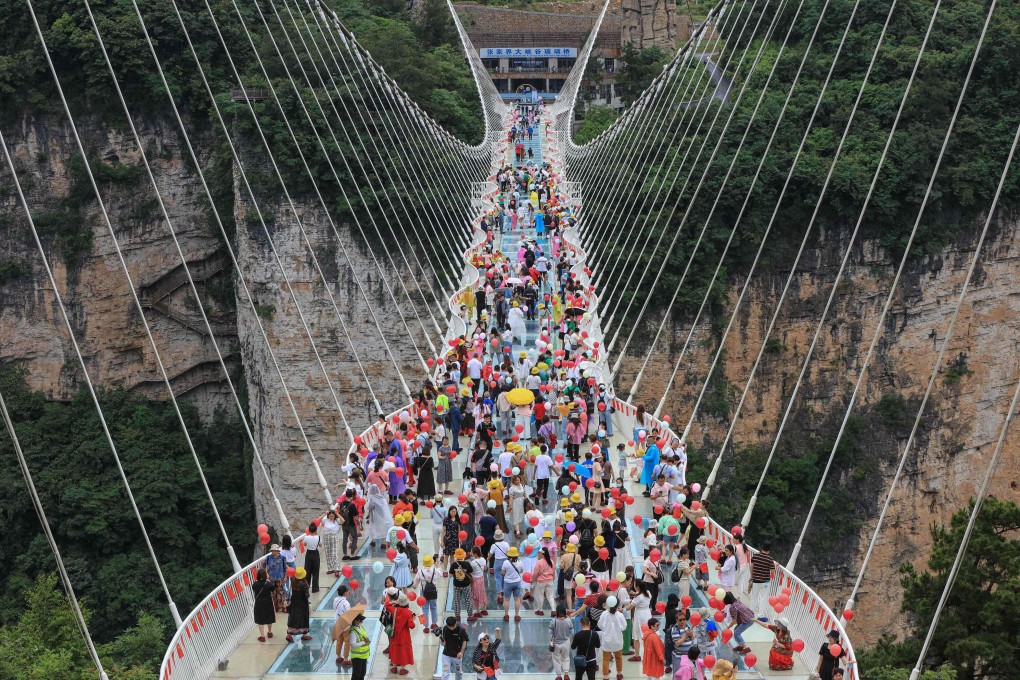 People walk on a glass-bottomed skywalk in Zhangjiajie, in China’s central Hunan province, on June 20. China may well be able to avoid a sudden plunge in asset prices. Photo: AFP