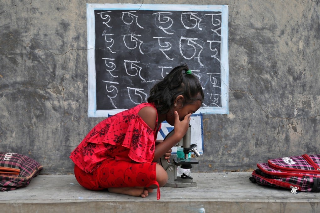 A girl with no access to internet facilities and gadgets uses a microscope as she attends an open-air class outside a house with its walls converted into blackboards as schools remained closed at a village in the Indian state of West Bengal on September 13. Photo: Reuters