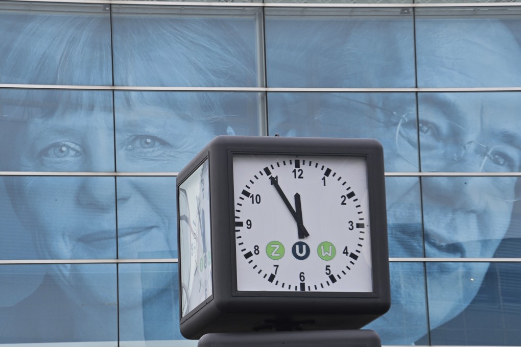 A clock displays the time in front of posters of German Chancellor Angela Merkel and Armin Laschet in Berlin on September 27. German voters called time on Merkel’s centre-right Christian Democratic Union last month, part of a global leftward shift amid an uneven recovery from the pandemic. Photo: DPA