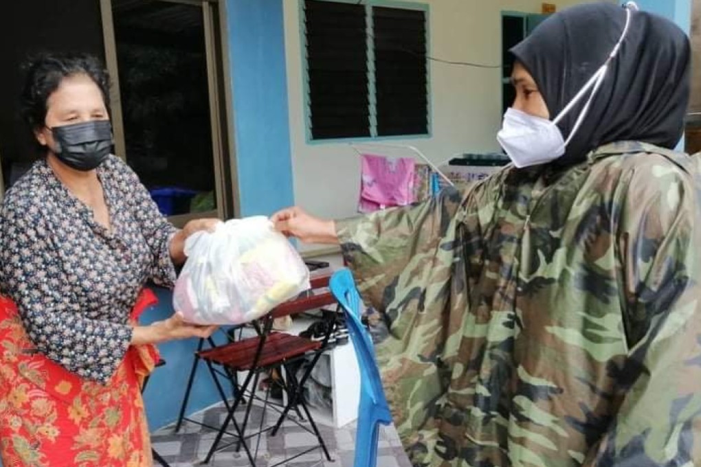 A woman in Phuket, Thailand, receives a Life Bag containing enough basic food items to feed a family of four for four days, distributed by One Phuket, an alliance of small tourism businesses.