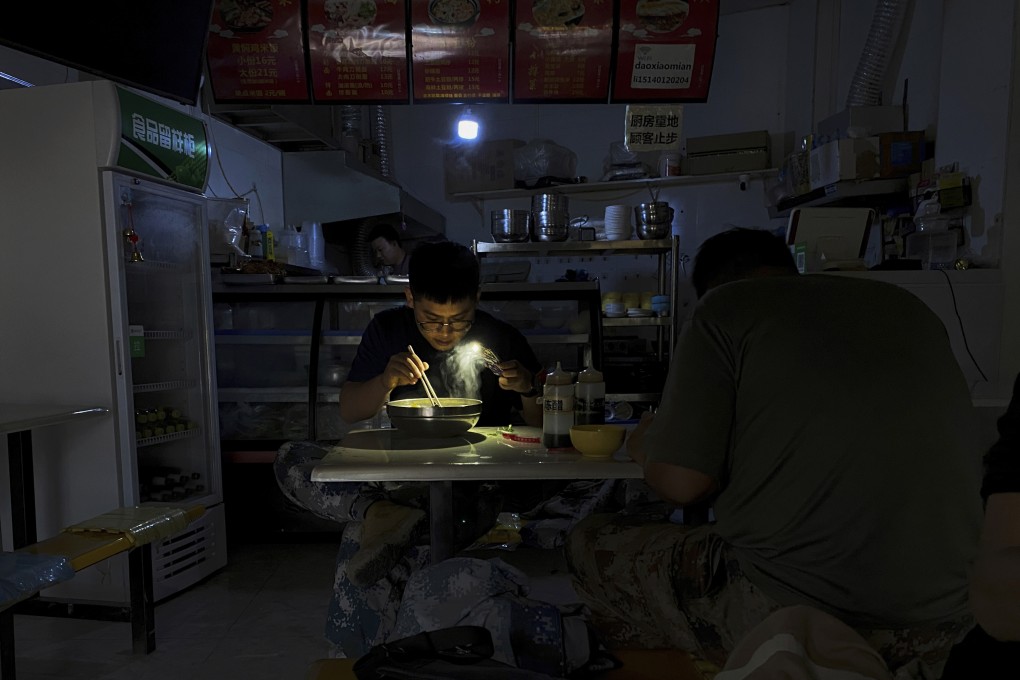 A man eats breakfast by the light of his smartphone in a restaurant during a blackout in Shenyang in China’s Liaoning province on September 29. Photo: AP