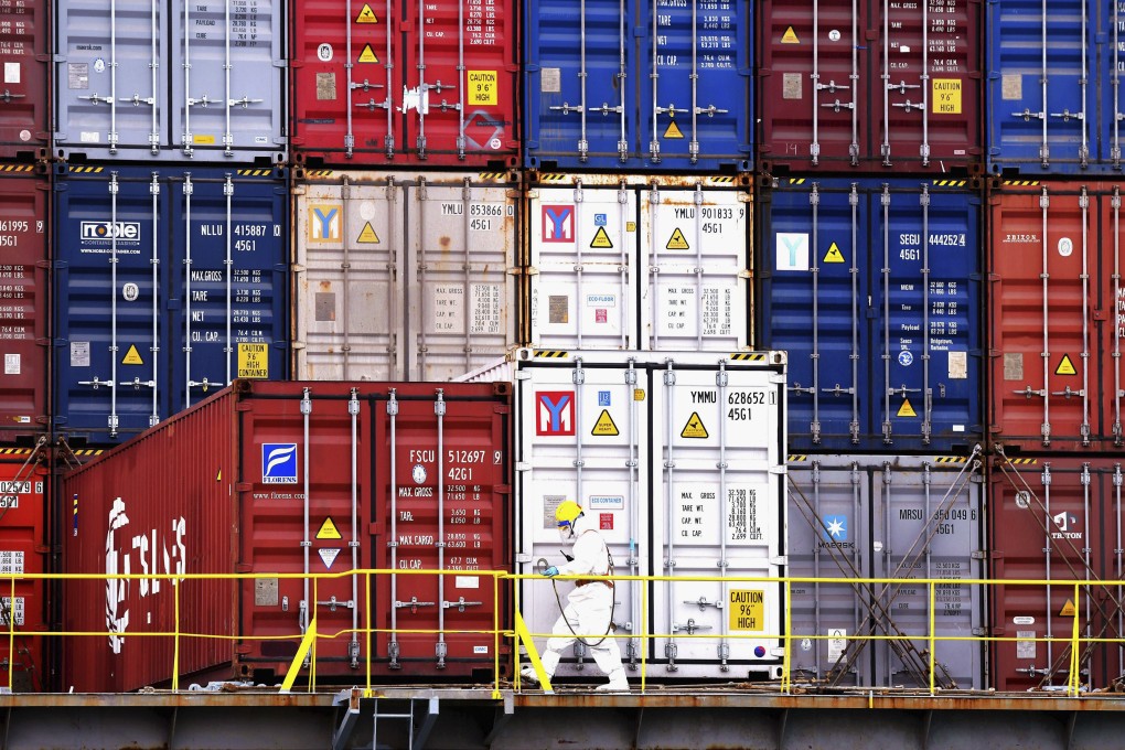 A person in protective overalls works near containers on a ship in Qingdao, in east China’s Shandong province. Supply chain issues have forced some exporters to resort to air freight, which can cost 10 times as much as shipping by sea. Photo: AP
