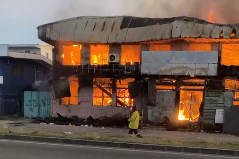 A fireman walks past a burning hardware store in Honiarain, Solomon Islands. Photo: Stewart K via Reuters