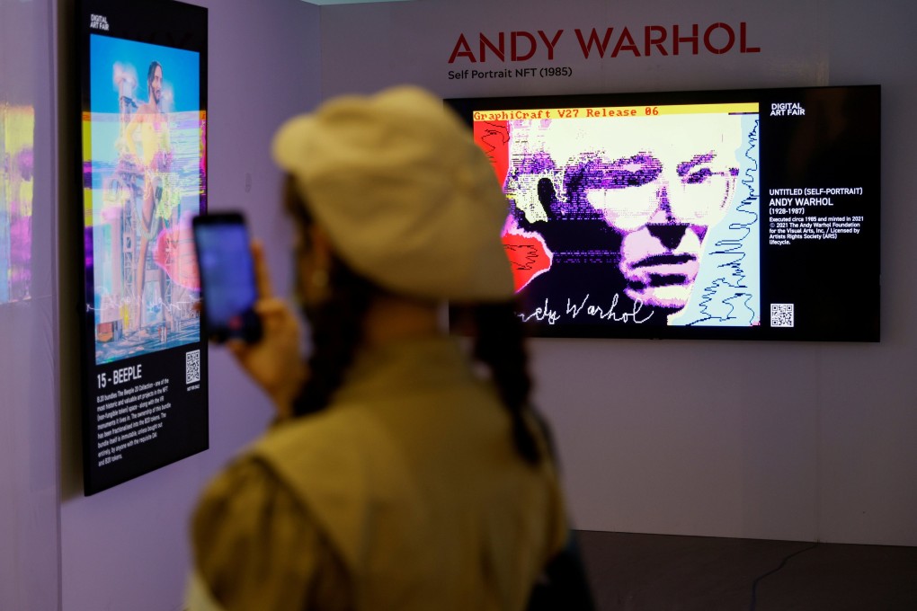 A visitor takes a photo in front of digital work ‘Untitled (Self-Portrait)‘ by Andy Warhol and digital artist Mike Winkelmann, known as Beeple, at the Digital Art Fair, in Hong Kong, September 30, 2021. Photo: Reuters