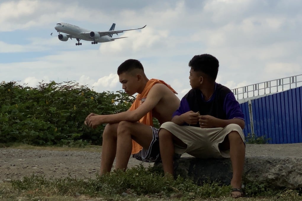A plane prepares to land as villagers look on in the Philippines. Photo: EPA