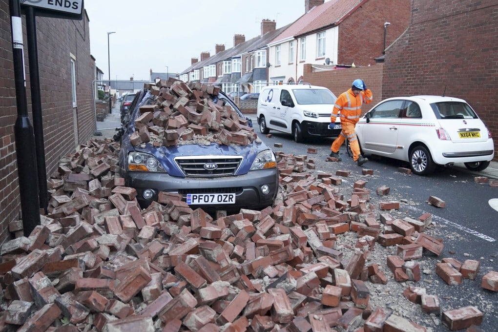 A man in the north of England walks past a car lying under fallen bricks after powerful wind gusts battered Britain during “Storm Arwen”. The Met Office issued a rare red warning for wind from 3pm on Friday to 2am on Saturday. Photo: PA via AP