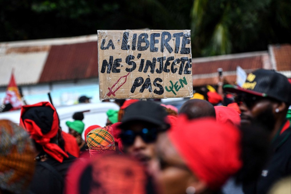 A demonstrator holds a sign reading ‘Freedom can’t be injected’ during a protest march over coronavirus measures and social grievances in Pointe-a-Pitre in the French Caribbean island of Guadeloupe on Saurday. Photo: AFP